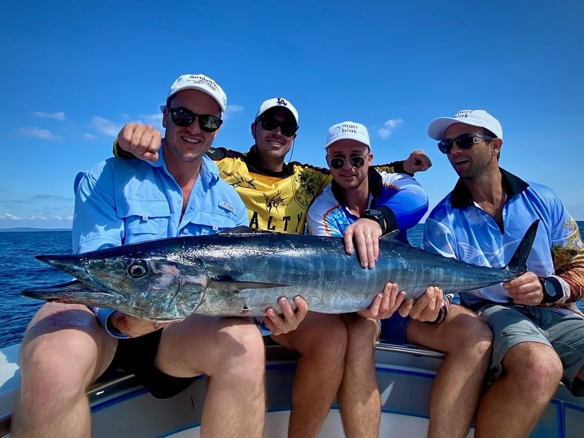 A Big Wahoo Being Held By A Group Of Mates Fishing Vanuatu with Ocean Blue